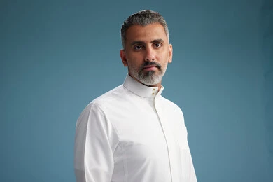 صورة مقربه لرجل عربي  سعودي خليجي يرتدي ثوب ابيض  , النظر الى الكاميرا, الوقوف بثقه, خلفيه زرقاء
