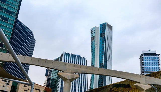 **Advanced urban scene in the heart of Riyadh**, featuring the King Abdullah Financial District (KAFD) towers with reflective glass facades and elegant architectural bridges, reflecting economic ambition and the contemporary architectural identity of the Kingdom of Saudi Arabia