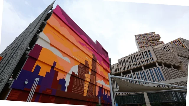 تصوير معماري لمدينة الرياض الحديثة، مبانٍ شاهقة بتصميم مستقبلي في منطقة الأعمال مركز الملك عبدالله المالي، مع عناصر فنية حضرية تضيف طابعاً إبداعياً يعكس رؤية المملكة للتطوير العمراني