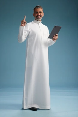 بورتريه لرجل عربي سعودي  خليجي يرتدي الثوب  الابيض يستخدم جهازاً لوحياً رقمياً, كامل الجسم, خلفيه زرقاء