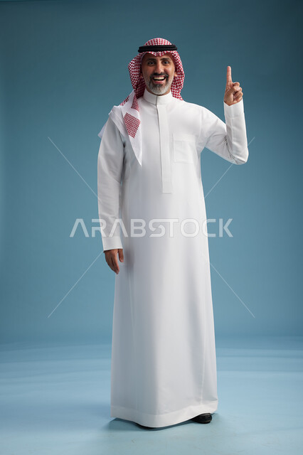 بورتريه لرجل  عربي سعودي  خليجي واثق يرتدي الثوب الابيض والشماغ  ويبتسم, اشارات وحركات متنوعه, خلفيه زرقاء