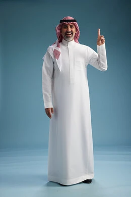 A portrait of a confident Arab Saudi Gulf man wearing a white thobe and a shemagh, smiling, with various gestures and movements, against a blue background.