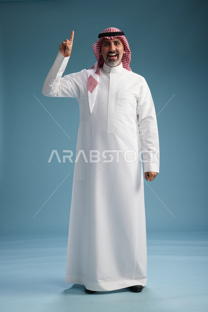 بورتريه لرجل  عربي سعودي  خليجي واثق يرتدي الثوب الابيض والشماغ  ويبتسم, اشارات وحركات متنوعه, خلفيه زرقاء