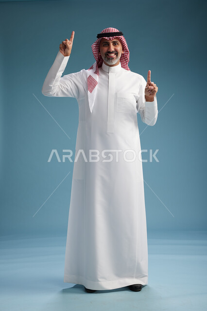 بورتريه لرجل  عربي سعودي  خليجي واثق يرتدي الثوب الابيض والشماغ  ويبتسم, اشارات وحركات متنوعه, خلفيه زرقاء