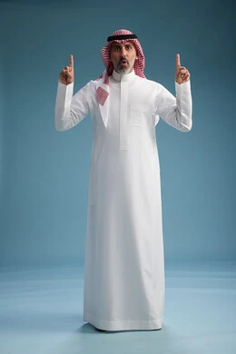 A portrait of a confident Arab Saudi Gulf man wearing a white thobe and a shemagh, smiling, with various gestures and movements, against a blue background.