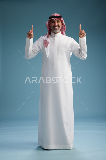 بورتريه لرجل  عربي سعودي  خليجي واثق يرتدي الثوب الابيض والشماغ  ويبتسم, اشارات وحركات متنوعه, خلفيه زرقاء