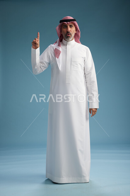 A portrait of a confident Arab Saudi Gulf man wearing a white thobe and a shemagh, smiling, with various gestures and movements, against a blue background.