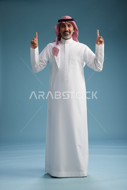 A portrait of a confident Arab Saudi Gulf man wearing a white thobe and a shemagh, smiling, with various gestures and movements, against a blue background.