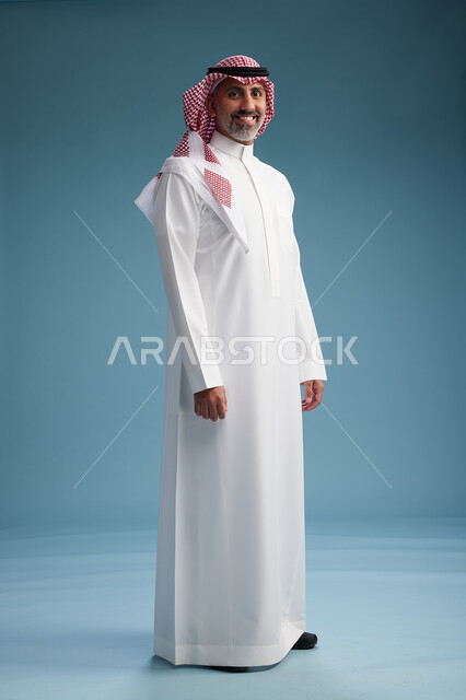 بورتريه لرجل  عربي سعودي  خليجي واثق يرتدي الثوب الابيض والشماغ  ويبتسم, اشارات وحركات متنوعه, خلفيه زرقاء