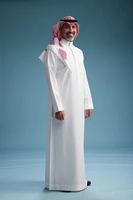A portrait of a confident Arab Saudi Gulf man wearing a white thobe and a shemagh, smiling, with various gestures and movements, against a blue background.