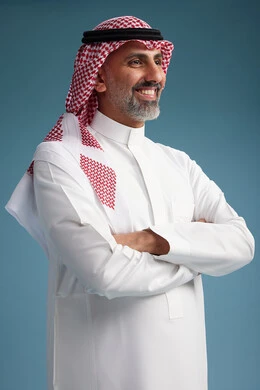 A portrait of a confident Arab Saudi Gulf man wearing a white thobe and a shemagh, smiling, with various gestures and movements, against a blue background.