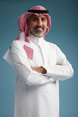 A portrait of a confident Arab Saudi Gulf man wearing a white thobe and a shemagh, smiling, with various gestures and movements, against a blue background.