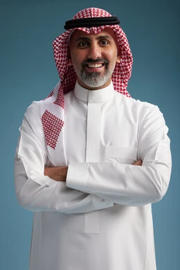 A portrait of a confident Arab Saudi Gulf man wearing a white thobe and a shemagh, smiling, with various gestures and movements, against a blue background.