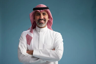 A portrait of a confident Arab Saudi Gulf man wearing a white thobe and a shemagh, smiling, with various gestures and movements, against a blue background.
