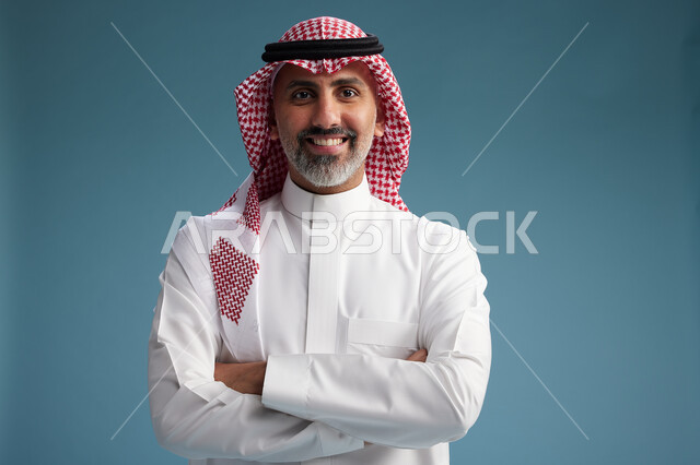 بورتريه لرجل  عربي سعودي  خليجي واثق يرتدي الثوب الابيض والشماغ  ويبتسم, اشارات وحركات متنوعه, خلفيه زرقاء