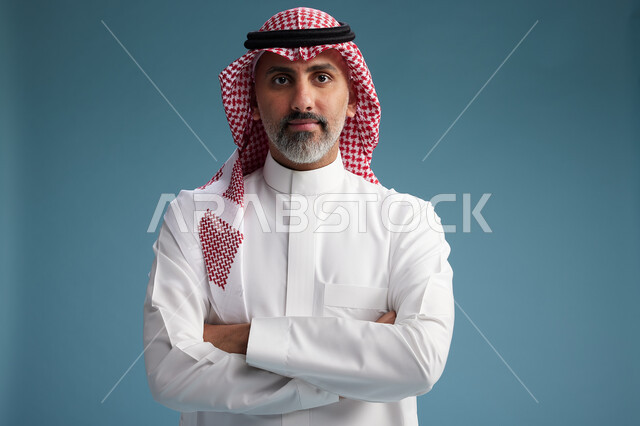 بورتريه لرجل  عربي سعودي  خليجي واثق يرتدي الثوب الابيض والشماغ  ويبتسم, اشارات وحركات متنوعه, خلفيه زرقاء