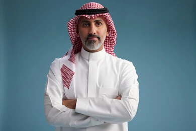 A portrait of a confident Arab Saudi Gulf man wearing a white thobe and a shemagh, smiling, with various gestures and movements, against a blue background.