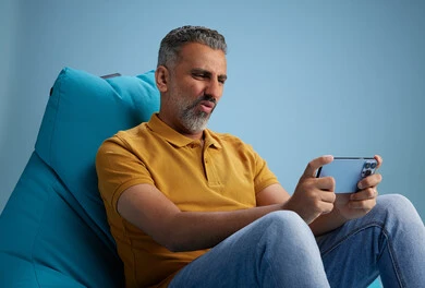 A portrait of an Arab Saudi Gulf man wearing casual attire sitting on a chair among blue flowers, with various gestures and movements, against a blue background.