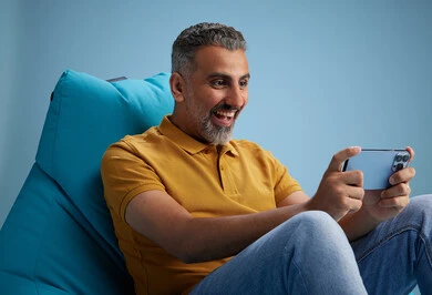 A portrait of an Arab Saudi Gulf man wearing casual attire sitting on a chair among blue flowers, with various gestures and movements, against a blue background.
