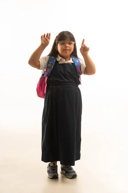 A small Arab Gulf Saudi girl with special needs is raising her index finger up in one hand, wearing a gray school uniform. She raises four fingers in the other hand, indicating the number four. The body is shown in full length, with a white background portrait.
