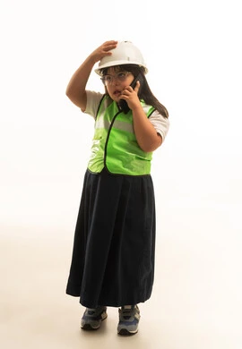 Gestures of shock and sadness, a young Arab Gulf Saudi girl suffering from Down syndrome wearing a gray school uniform and a white helmet, standing in front of the camera, wearing a reflective safety vest for engineers, full-body, portrait with a white background.