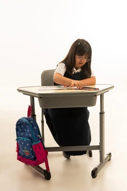 بنت صغيرة عربية خليجية سعودية من متلازمة داون ترتدي زي المدرسة الموحد لون كحلي تختار بين الالوان الخشبية المتعددة , التلوين و الرسم اثناء اليوم الدراسي , بورتريه خلفية بيضاء , الجسم بالطول الكامل