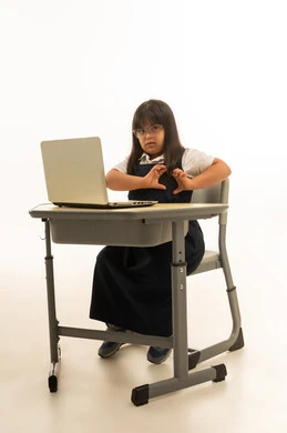 تشكيل علامة القلب ياليدين الصغيرتين , بنت عربية خليجية سعودية تعاني من متلازمة داون ترتدي زي مدرسي موحد لون كحلي , النظر الى الكاميرا , ايماءات الحب , الاعتماد على الاجهزة التقنية في المنظومة التعليمية السعودية , الجسم بالطول الكامل , بورتريه خلفية بيضاء