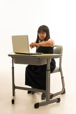 ضم اليدين امام جهاز الحاسب المتنقل علامة القلب , بنت صغيرة عربية خليجية سعودية من ذوي الهمم ترتد زي مدرس موحد لون كحلي , استخدام الاجهزة الحديثة في نظام التعليم السعودي , الجسم بالطول الكامل , بورتريه خلفية بيضاء