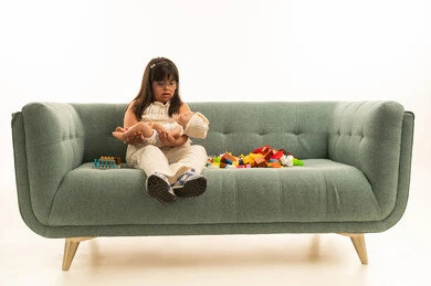 العاب فك و تركيب و تنمية المهارات الذهنية , بنت صغيرة عربية خليجية سعودية من اصحاب الاحتياجات الخاصة تحمل دمية صغيرة , ارتداء الزي الكاجوال اللون البيج , الجسم بالطول الكامل , بورتريه خلفية بيضاء