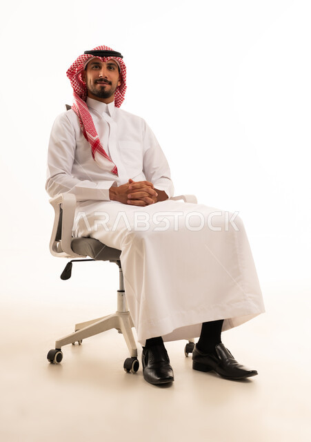 رجل سعودي بالزي التقليدي يجلس على كرسي مكتب
