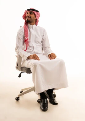 رجل سعودي بالثوب التقليدي يجلس على كرسي مكتب