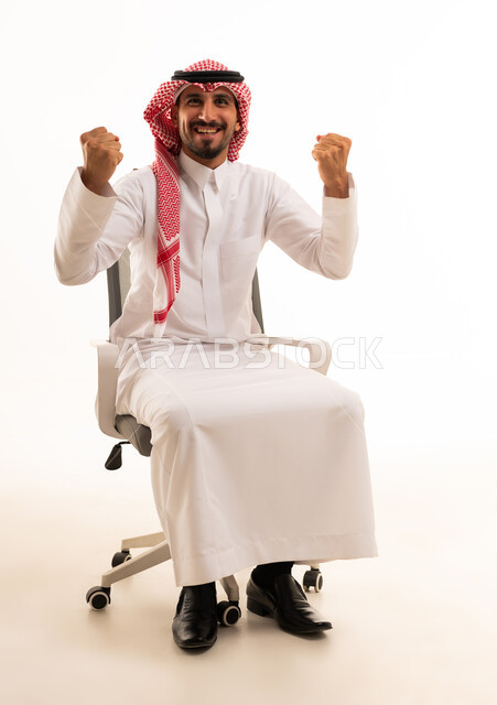 رجل سعودي يحتفل بالنجاح على كرسي مكتب