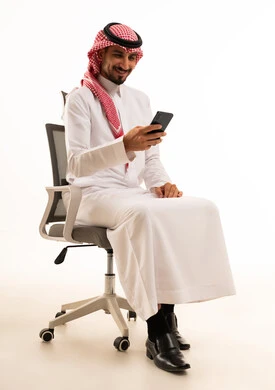 رجل سعودي بالزي التقليدي يستخدم الهاتف الذكي