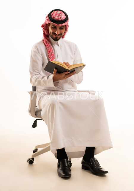 Saudi Man Reading Book on Office Chair Studio Shot