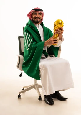 رجل سعودي يحمل مجسم كأس العالم مع العلم الوطني