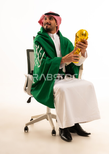 رجل سعودي يحمل مجسم كأس العالم والعلم الوطني