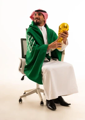 رجل سعودي يحمل مجسم كأس العالم والعلم الوطني رجل سعودي يحمل مجسم كأس العالم والعلم الوطني