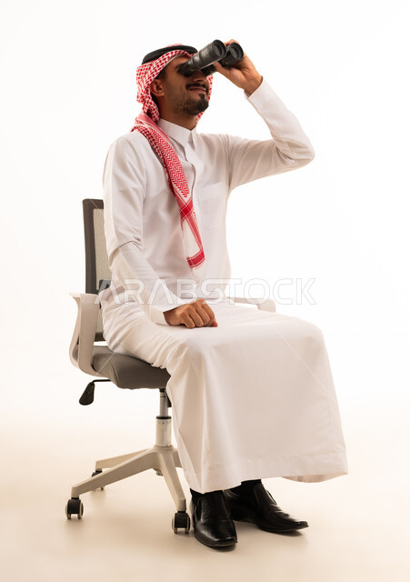 رجل سعودي يستخدم منظار ثنائي على كرسي مكتب للرؤية