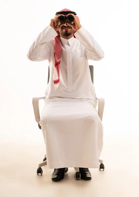 رجل سعودي يستخدم المنظار على كرسي مكتب