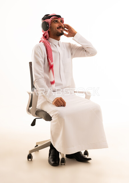 رجل سعودي مع سماعات رأس على كرسي مكتب