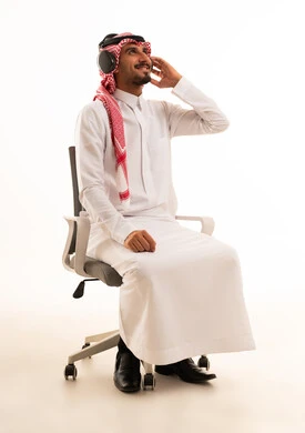 رجل سعودي مع سماعات رأس على كرسي مكتب