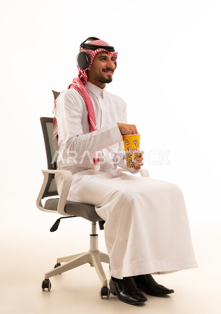 رجل سعودي يرتدي سماعات ويأكل الفشار