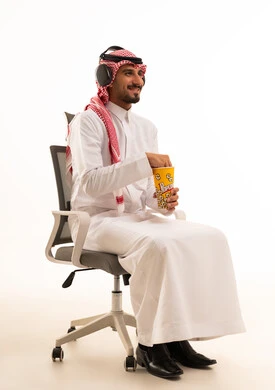 رجل سعودي يرتدي سماعات ويأكل الفشار