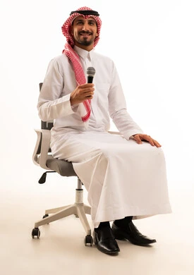 رجل سعودي يحمل ميكروفون على كرسي مكتب