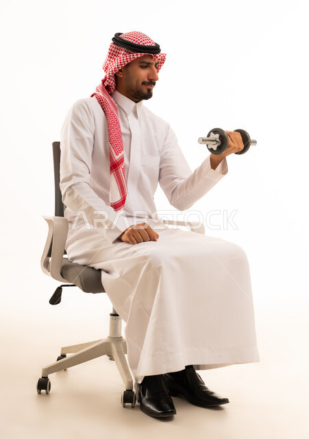 رجل سعودي يمارس تمارين القوة بالدامبل على كرسي مكتب