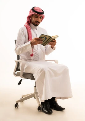 رجل سعودي بالزي التقليدي يقرأ القرآن الكريم
