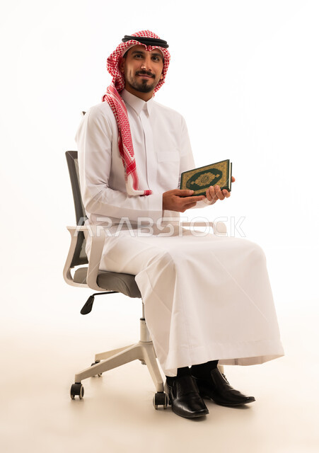 رجل سعودي بالزي التقليدي يمسك المصحف الشريف