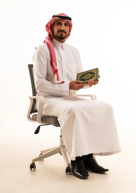 رجل سعودي بالزي التقليدي يمسك المصحف الشريف
