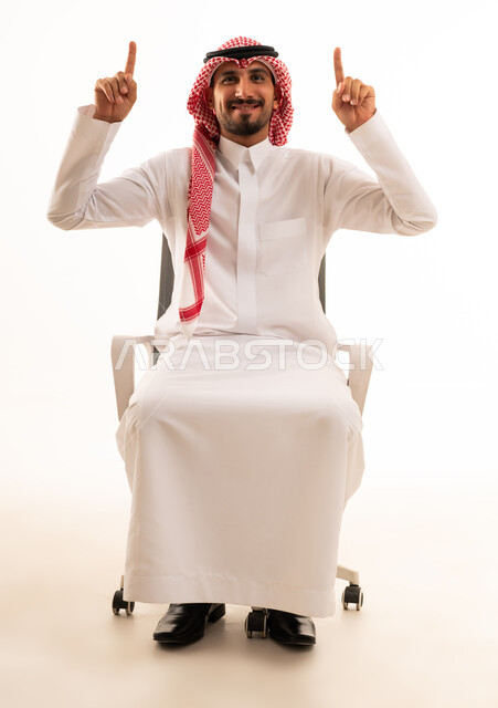 رجل سعودي بالزي التقليدي يشير للأعلى على كرسي