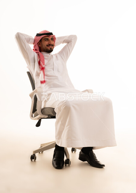 رجل سعودي بالزي التقليدي يسترخي على كرسي مكتب